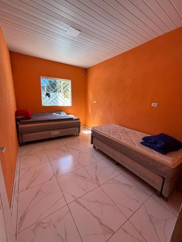 two beds in a room with orange walls at Recanto Enseada dos Corais in Cabo de Santo Agostinho