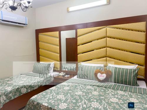 a bedroom with two beds and a glass table at Hotel white palace in Karachi