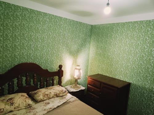 a bedroom with green wallpaper and a bed with a lamp at Tu Jardín Secreto Cachi in Cachí