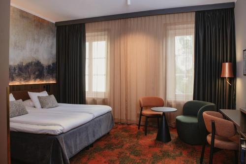 a hotel room with a bed and a chair at Home Hotel Bergmästaren in Falun