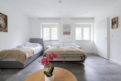 - une chambre avec 2 lits et une table fleurie dans l'établissement COY Apartments Purkersdorf - Garden Comfort for Work Family near Vienna, à Purkersdorf