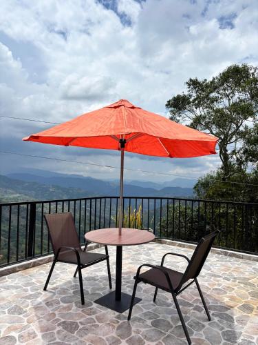 a table and two chairs under a red umbrella at Entre Montañas in Vergara