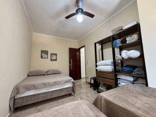 a bedroom with two beds and a ceiling fan at Apê 57 Ar Condicionado, Vista Mar, WiFi, Vaga, Completo in Praia Grande