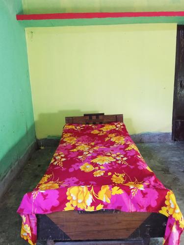 a bed with a red blanket with flowers on it at Jacobs Homestay Unit 1 Low Budget in North Lakhimpur