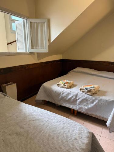 two beds with towels on them in a bedroom at Hotel Raglan in Mar del Plata