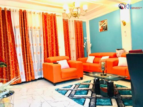 a living room with orange furniture and blue walls at IKN résidence in Douala