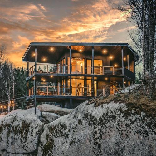 a house on top of a rock with a sunset at Tricera - Panoramic View near Quebec City in Lac-Beauport