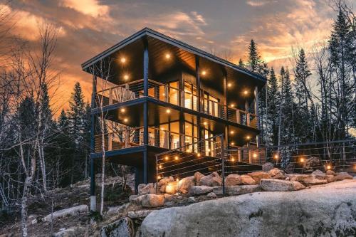 una casa en el bosque al atardecer con luces en Tricera - Panoramic View near Quebec City, en Lac-Beauport