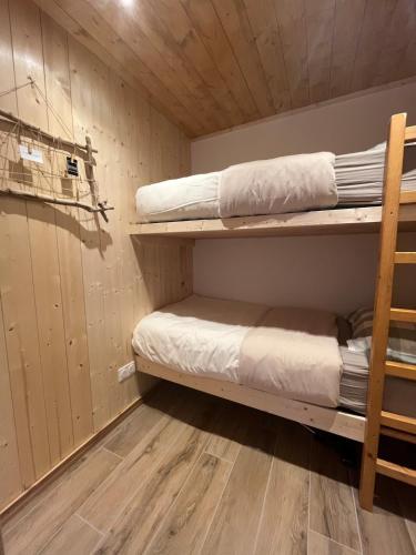 a room with two bunk beds and a wooden floor at Appartement au centre des Carroz in Arâches-la-Frasse