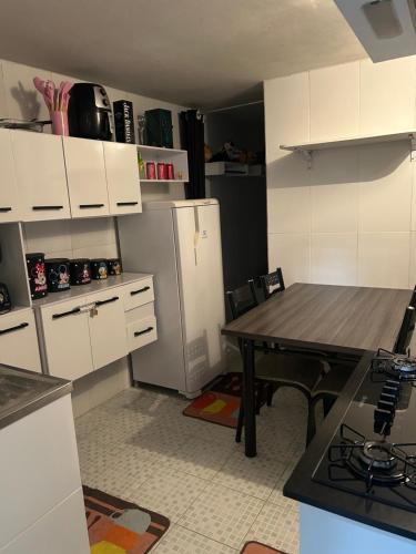 a kitchen with a table and a refrigerator at Casa da Amanda in São Thomé das Letras