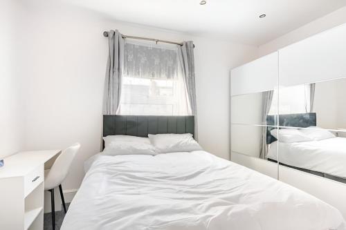 a white bedroom with a bed and a mirror at Burley Guest House in Headingley