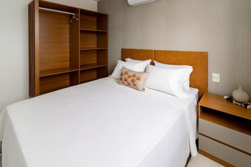 ein Schlafzimmer mit einem großen weißen Bett mit einem hölzernen Kopfteil in der Unterkunft 15 Andar, 2Q Suite Vista Mar, Ed Palmer, NOMDS in Insel Itaparica