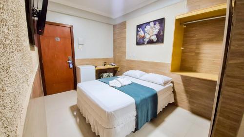 a bedroom with a bed with a blue blanket at Hotel Ipê in Belém