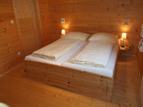 a bed in a wooden room with two pillows at Ferienhäuser Aura in Sankt Andrä bei Frauenkirchen