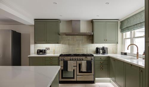 a kitchen with green cabinets and a stove top oven at Charming Family Retreat 4BR Marylebone in London