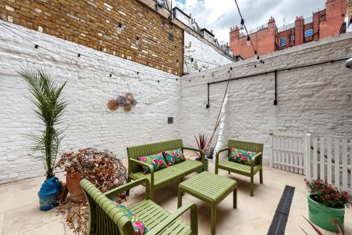 a patio with three green chairs with colorful pillows at Charming Family Retreat 4BR Marylebone in London