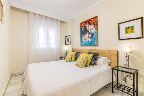 a bedroom with a large white bed with yellow pillows at Apartamento Costa Nagüeles 2hab. in Marbella