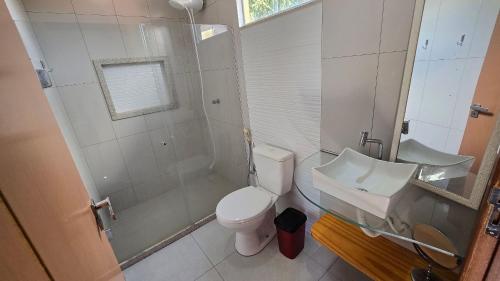 a bathroom with a toilet and a shower and a sink at Casa Temporada Brisa do Mar in Guriri