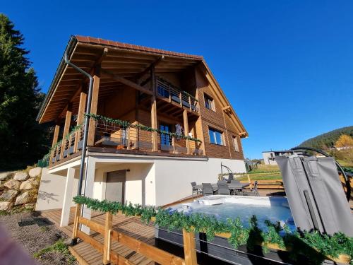 ジェラールメにあるChalet Bois le Havre du sotrè Gérardmer Sauna panoramique jacuzzi 14 personnes et 2 bébésのスイミングプールとバルコニー付きの家