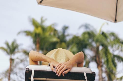 a woman wearing a hat sitting in a suitcase at Altos de la Viña, Wine Hotel & Spa in San Salvador de Jujuy