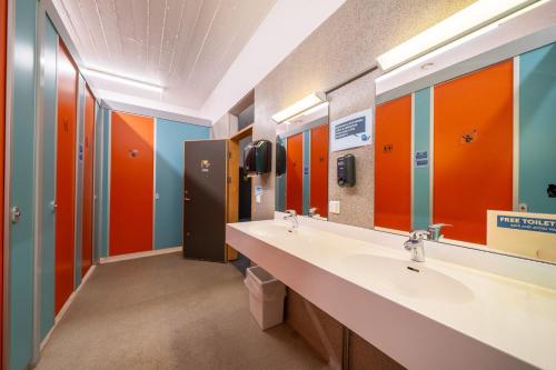 a bathroom with two sinks and orange and blue walls at Dalur - HI Eco Hostel in Reykjavík