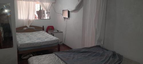 a small bedroom with two beds and a window at Casa de praia Coroados in Guaratuba