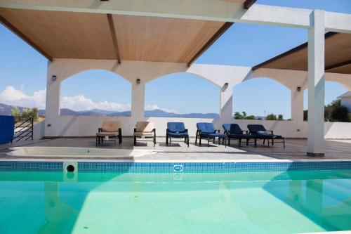 a swimming pool with chairs and a view of the mountains at Lirios Tiny House en Valle de Guadalupe in Valle de Guadalupe