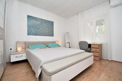 a white bedroom with a bed and a desk at Apartment Martelina in Manjadvorci