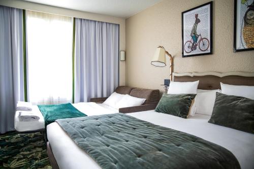 a hotel room with two beds and a bike on the wall at Hotel Novotel Domaine de Maffliers - Paris Val-d'Oise in Maffliers