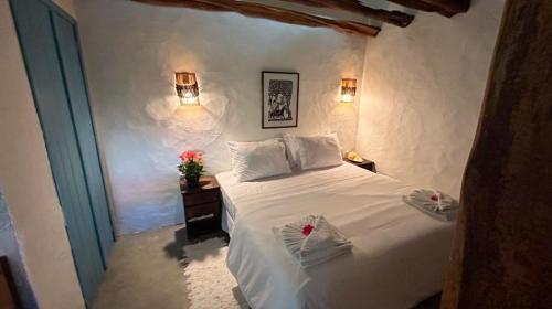 a bedroom with a white bed with two towels on it at Pousada Tatuamar Café & Bistrô - 150 m da praia in Pôrto de Pedras