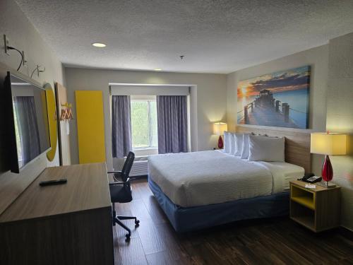 a hotel room with a bed and a desk at Days Inn & Suites by Wyndham Tampa/Raymond James Stadium in Tampa