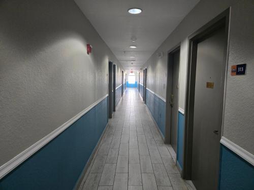 a long hallway with blue and white walls and a hallway sidx sidx sidx at Days Inn & Suites by Wyndham Tampa/Raymond James Stadium in Tampa