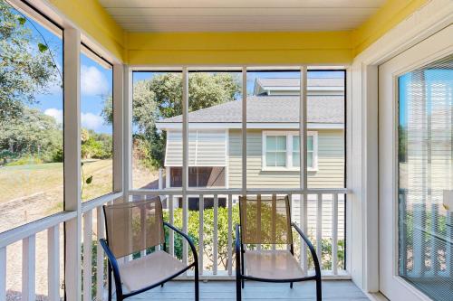 a screened in porch with two chairs and windows at Pelican Bay 42 in Isle of Palms