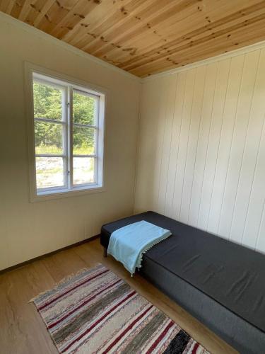 a bedroom with a bed in a room with a window at Skokkelvika gård in Vestvågøya