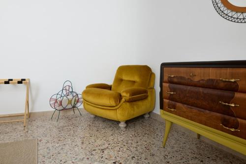 a yellow chair sitting in a room next to a dresser at Oltre Natura in Canneto Pavese