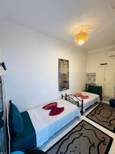 Un dormitorio con dos camas y una lámpara de araña. en Dar Beldi, en Marrakech