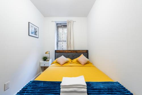 a bedroom with a yellow and blue bed with a window at 2 BD Domestic Dwelling in Manhattan Valley in New York