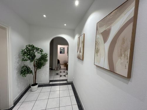 a hallway with white walls and a potted plant at Perfekt für 6-8! Küche Parkplätze Flughafen in Hallbergmoos