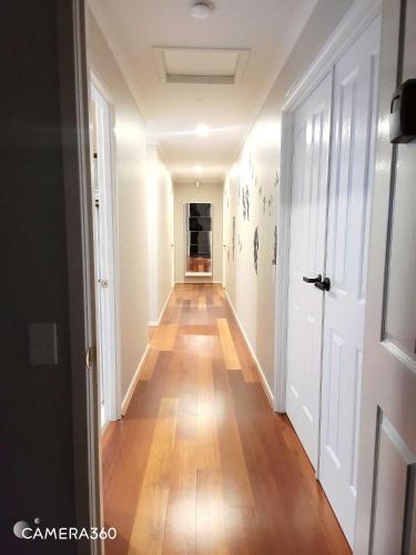 an empty hallway with a wooden floor and white walls at A Traveller's abode - Room 3 in Craigieburn