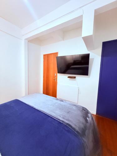 a bedroom with a blue bed and a tv at MAKTVB Europa - Hostal Boutique in Santiago