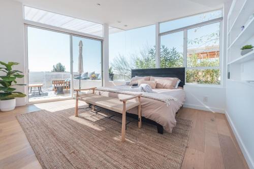 Schlafzimmer mit einem Bett, einer Bank und Fenstern in der Unterkunft Industrial&Stylish 3 bedroom 3 bathrooms Home With Views and Hot tub in Los Angeles