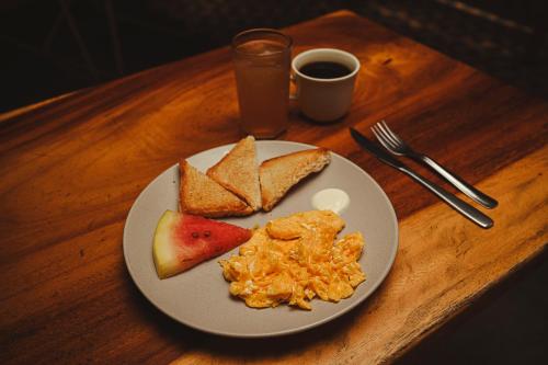 a plate of breakfast food with eggs and fruit on a table at Republica Hostel Santa Marta in Santa Marta