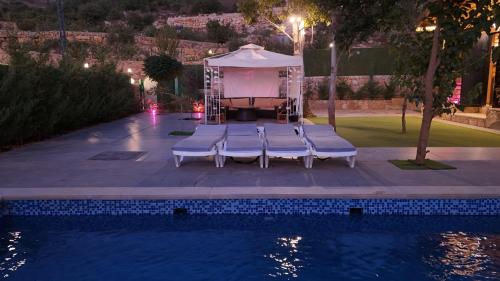 un gruppo di sedie accanto a una piscina di notte di The Wood House a Maasser El Chouf