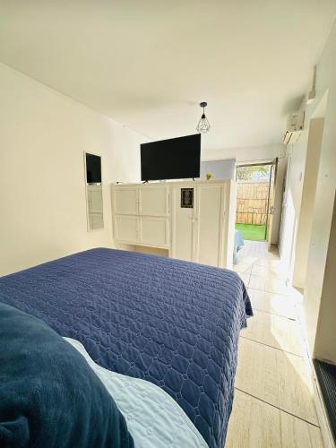 a bedroom with a blue bed and a flat screen tv at MAKTVB Europa - Hostal Boutique in Santiago