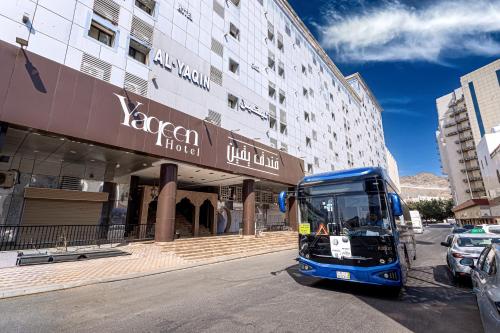 a blue bus parked in front of a building at فندق يقين مكة in Makkah
