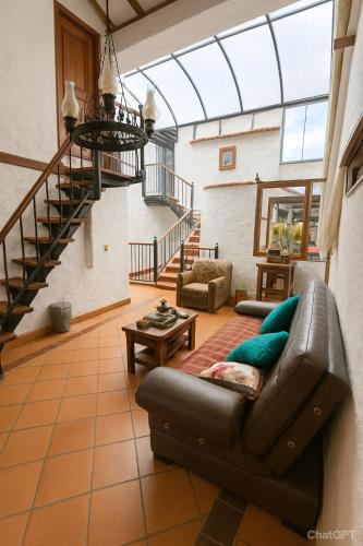 a living room with a leather couch and stairs at Hotel - Hospedería Villa Palva in Villa de Leyva