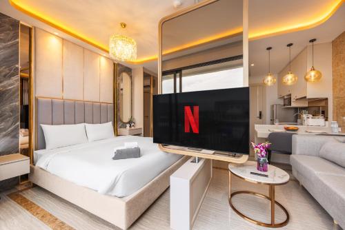 a bedroom with a large flat screen tv and a couch at Bellevue Lagoon Premium Apart Hotel by TropicLook in Laguna Phuket
