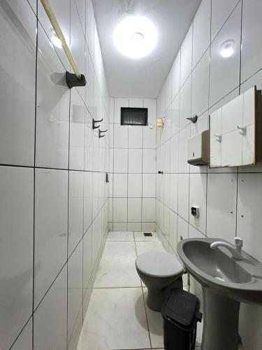 a white bathroom with a toilet and a sink at Hotel Sagrada Família in Montes Claros