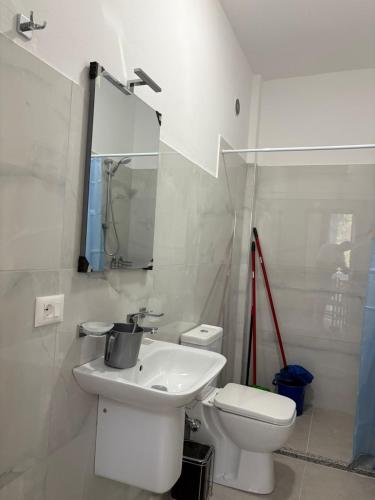 a white bathroom with a toilet and a sink at Vila Zyle in Velipojë