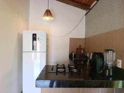 a kitchen with a white refrigerator and a stove at Casa Xandó in Porto Seguro